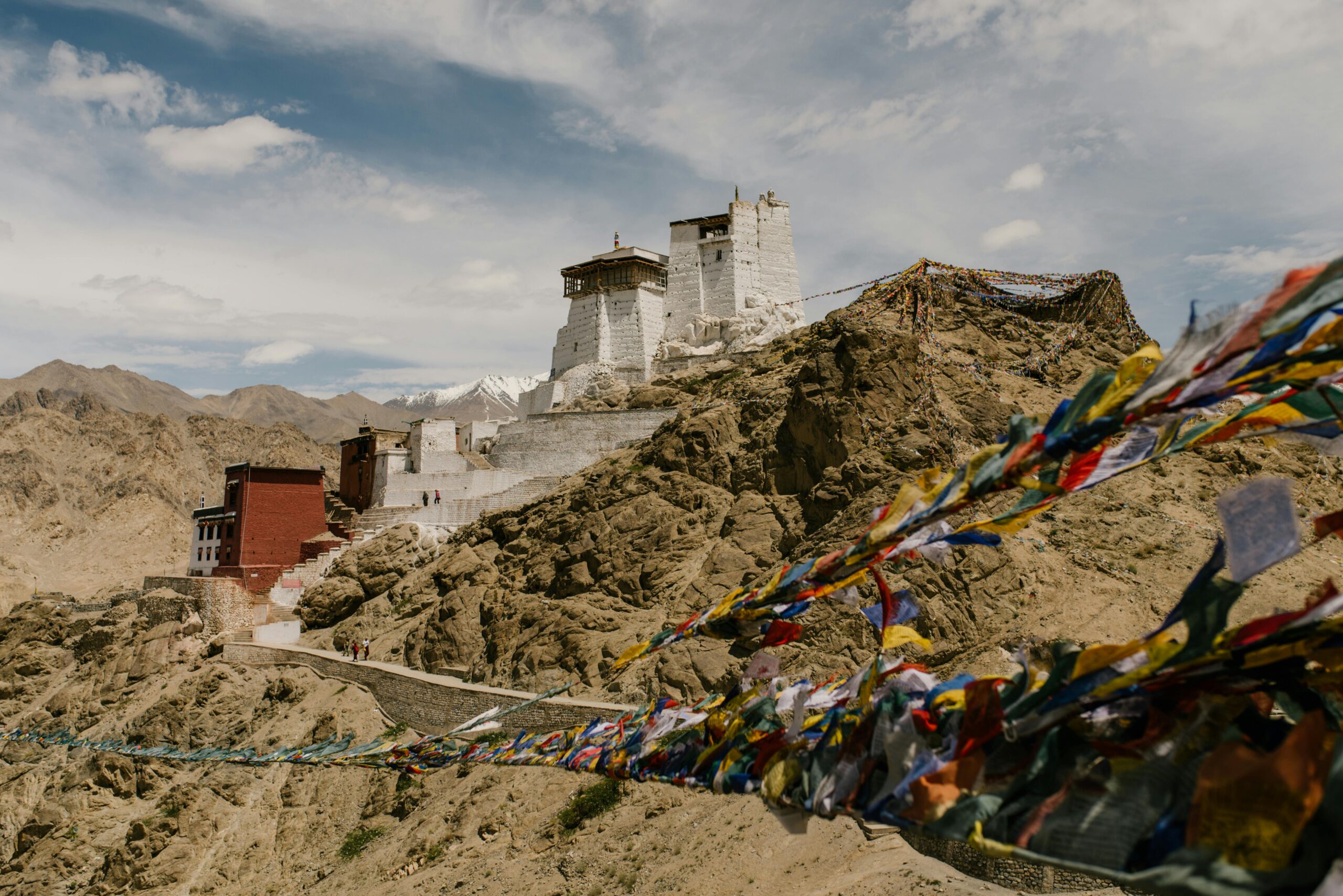 Stunning view of Namgyal Tsemo Monastery in the Himalayas with prayer flags waving in the wind.